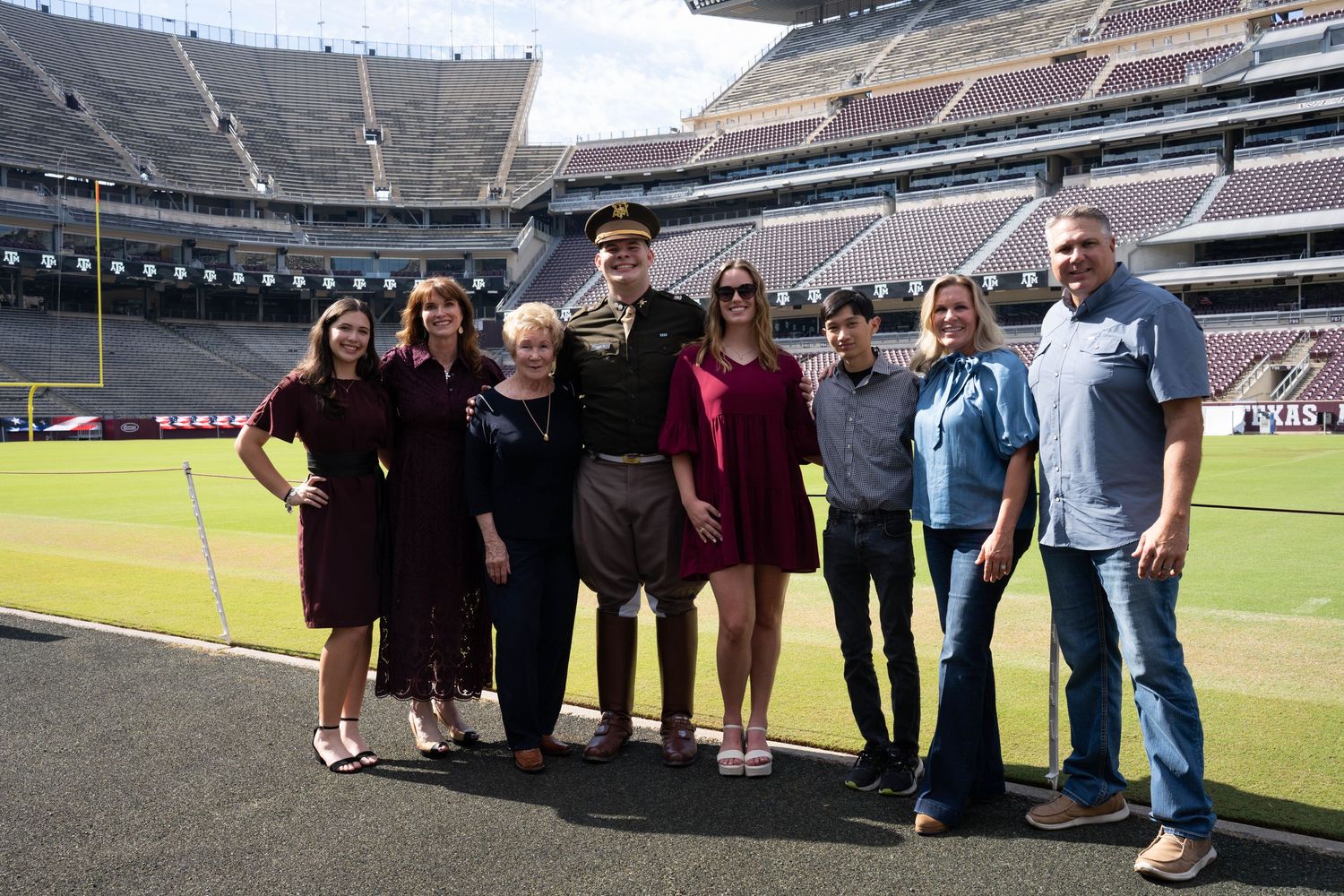 Family group photo with military officer at a college football stadium on a sunny day.