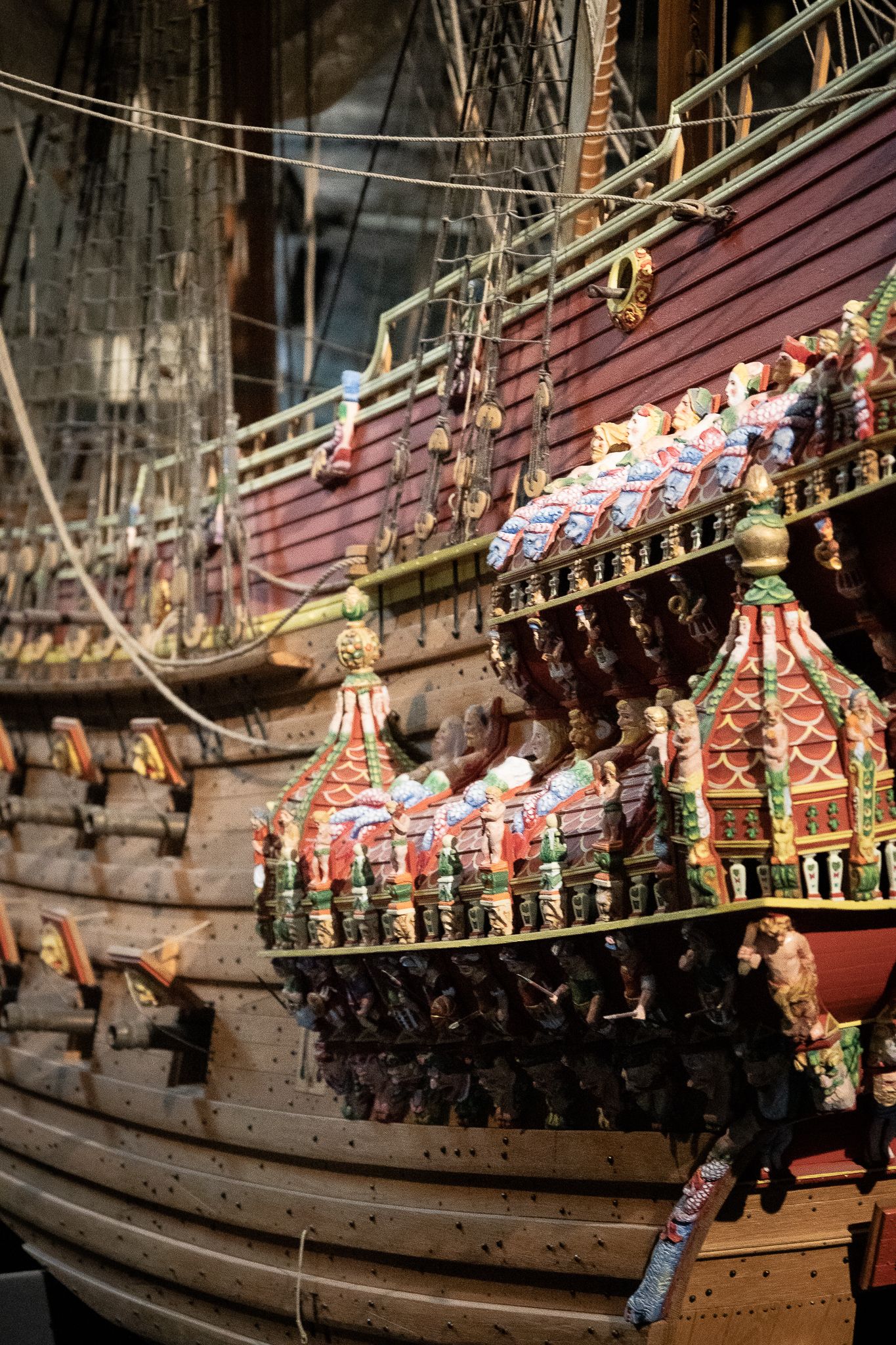Detailed scale model of an ornate 17th-century wooden sailing warship with colorful carved decorations and rigging.