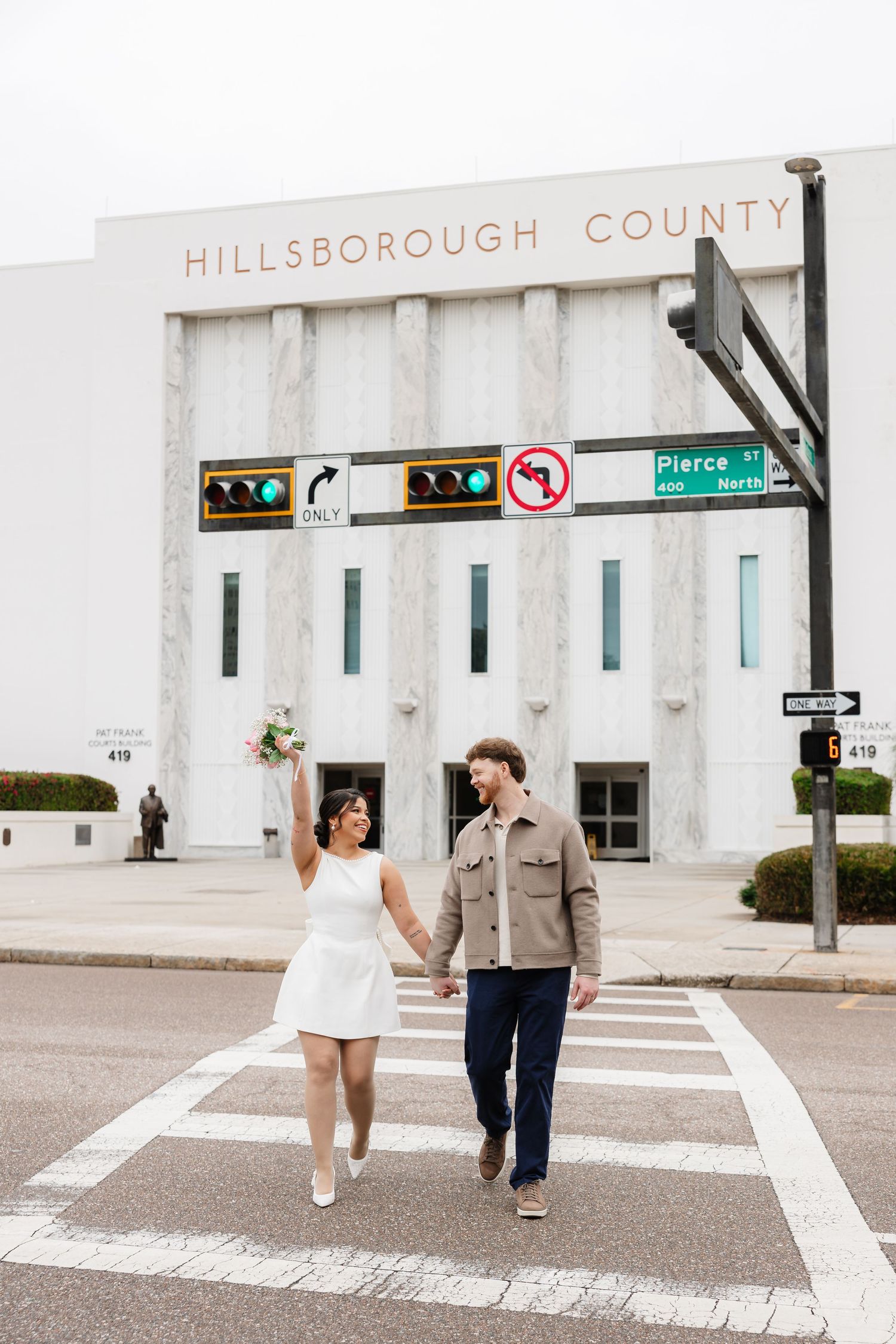 A couple walks across a crosswalk in front of the Hillsborough County building in downtown Tampa.