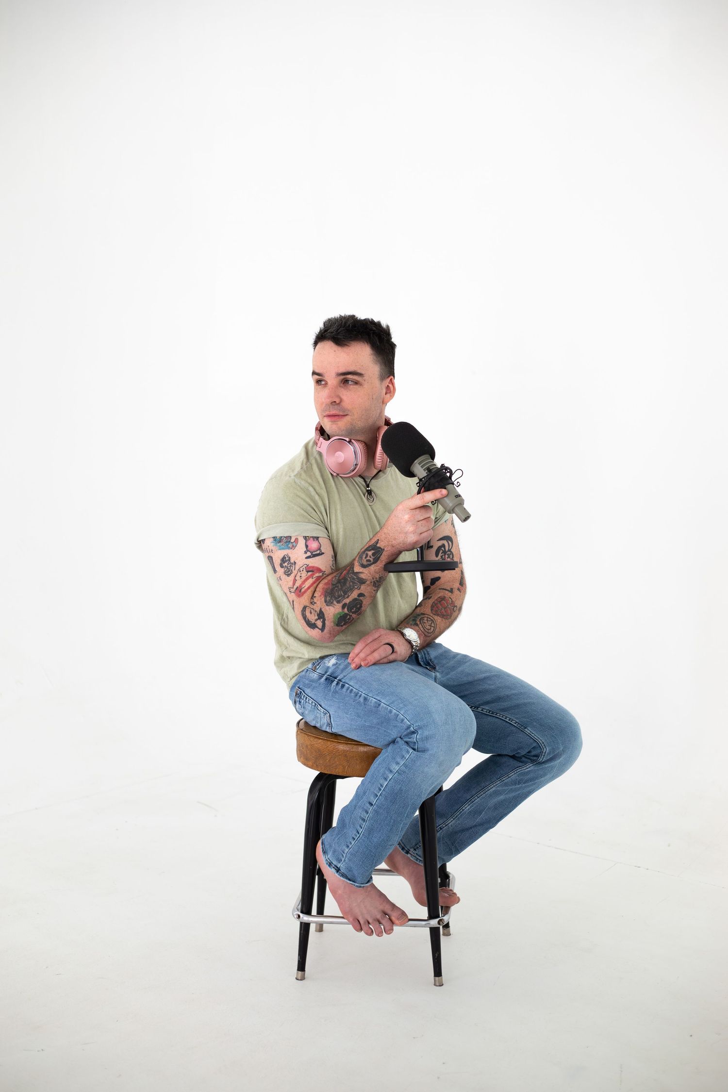 Person in mint green polo shirt sitting on stool in studio setting.