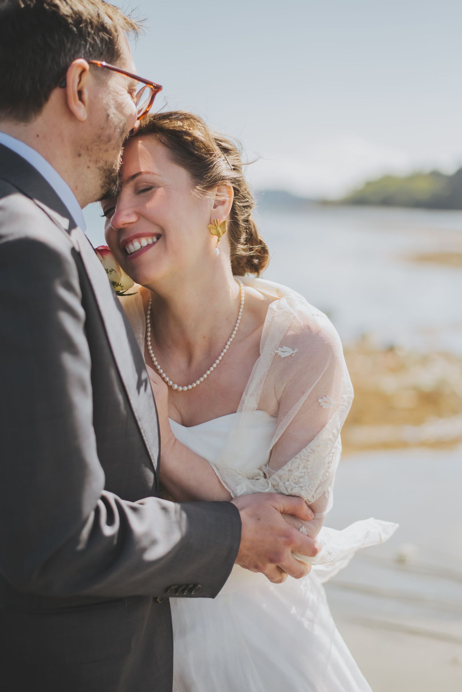 A romantic wedding couple shares an intimate moment by the water's edge on their special day.