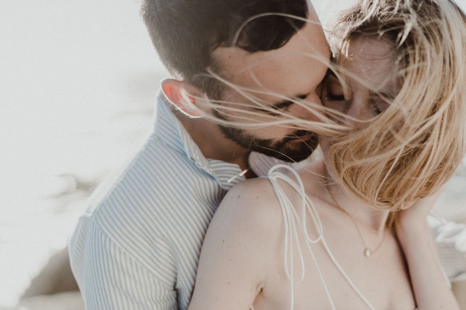 Emotional elopement moment on Miramar Beach, Portugal — couple embracing in the wind, captured by an elopement photographer in Portugal.