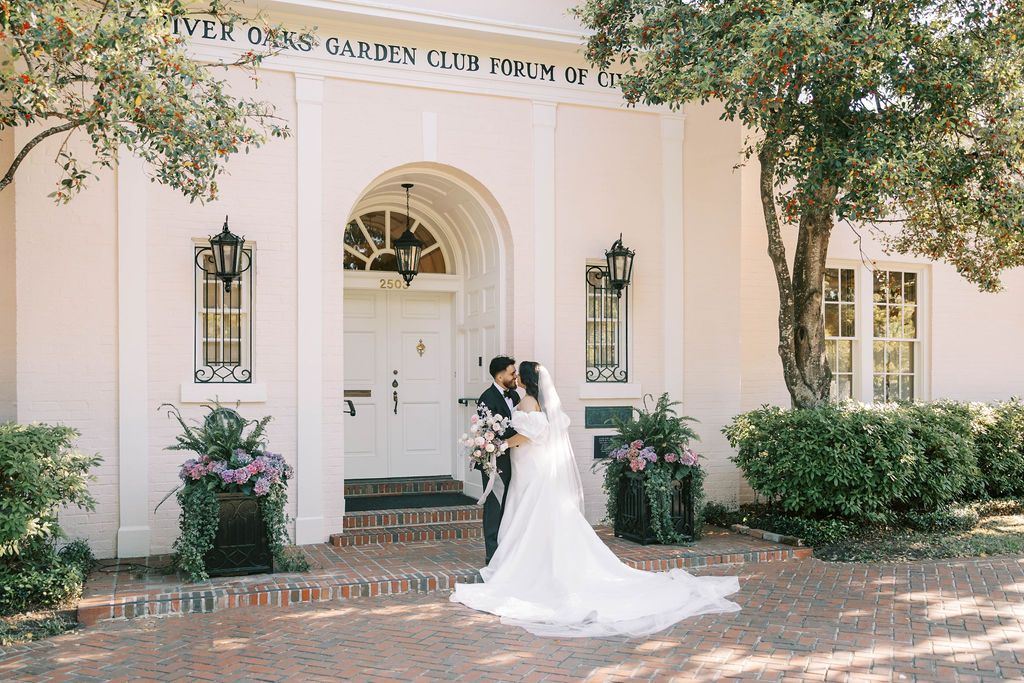 Elegant white wedding venue entrance with classic architecture and lush greenery.