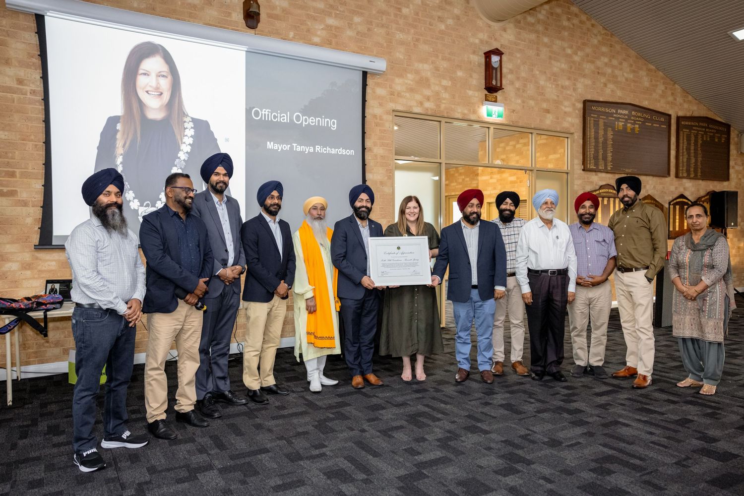 A group of people in business attire stand together in front of a presentation screen in a conference room.