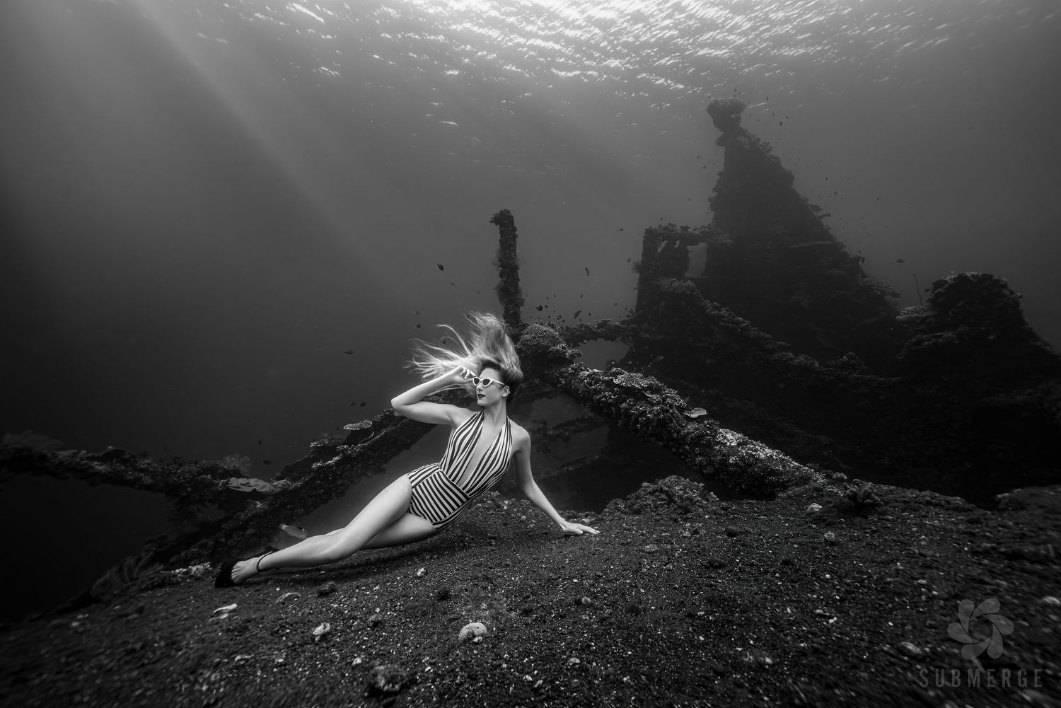 Underwater fashion photo with flowing red dress and nurse sharks swimming in crystal clear turquoise waters.