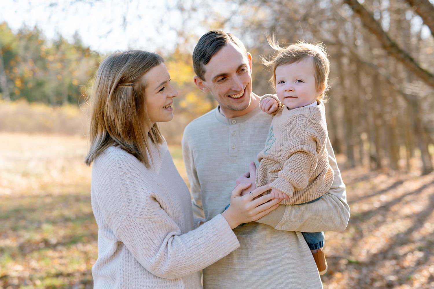 Family enjoying a casual outdoor photoshoot on green grass in a summer garden setting.