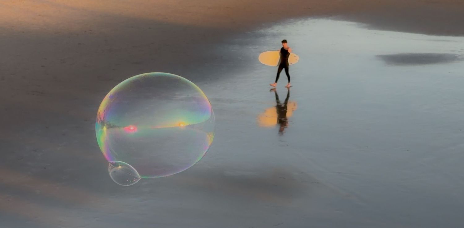 A person creates large soap bubbles at sunset against a cloudy sky, creating a magical outdoor display.