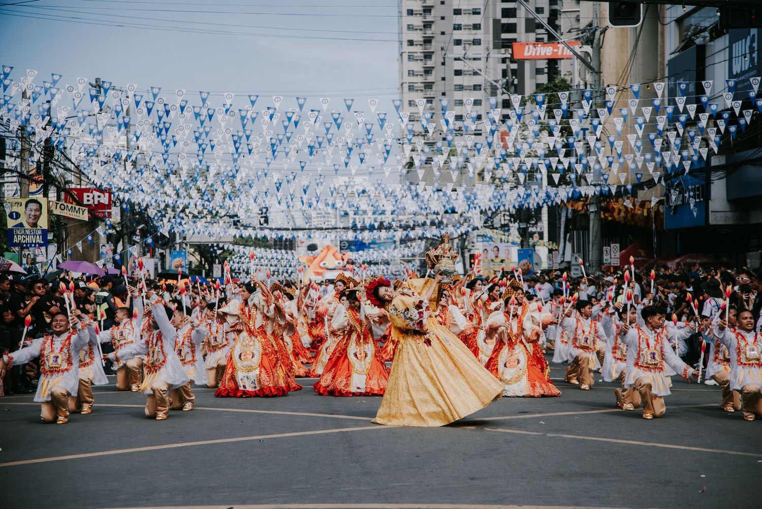 Large crowd of festival participants in colorful costumes gathered on a city street.