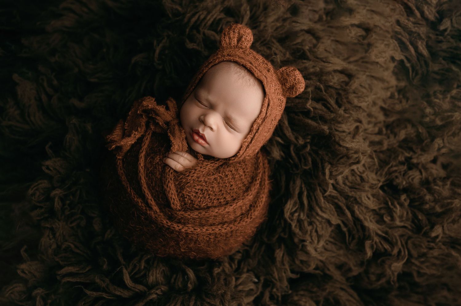 Seven artistic newborn photography portraits in brown tones showing sleeping baby wrapped in soft textured fabrics.
