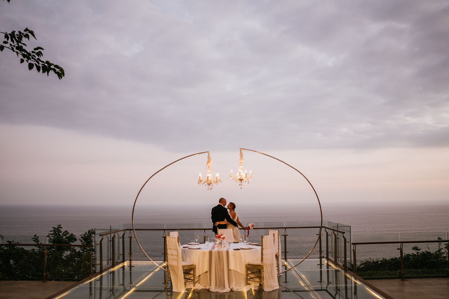 Modern circular wedding arch setup against dramatic sunset sky.