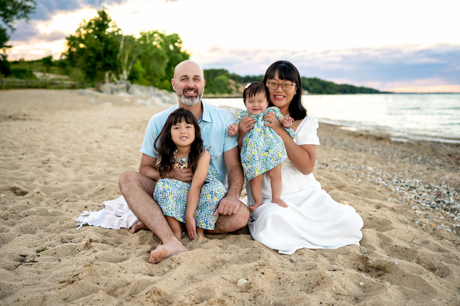 Family relaxes and plays together on beautiful sandy beach at sunset.