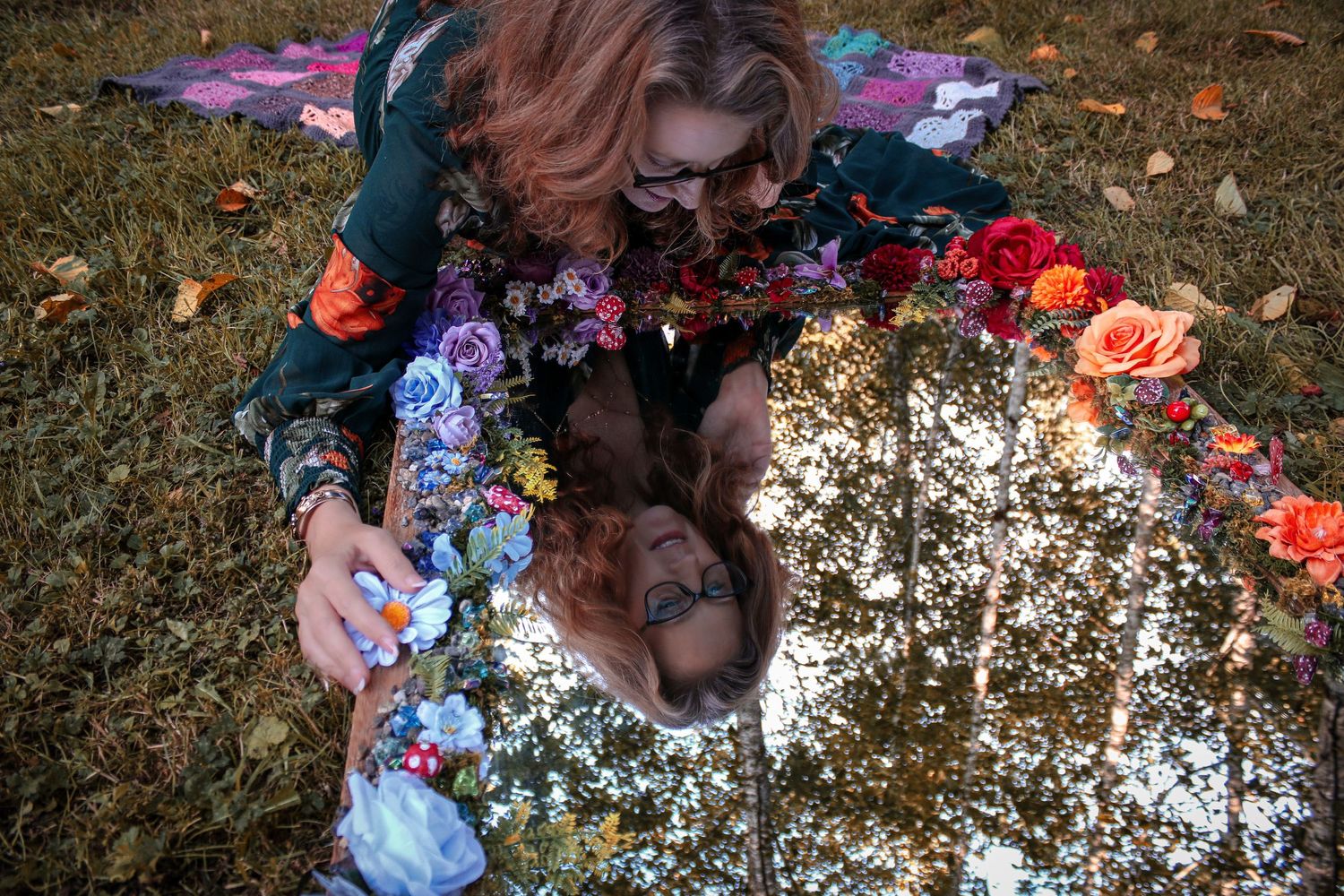 A collection of decorative flowers arranged in a soft natural outdoor setting with scattered petals on the ground.
