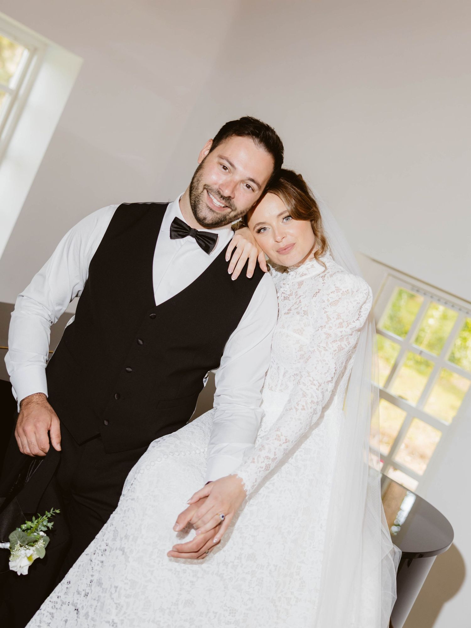 A black and white wedding photo showing details of a bride in an off-shoulder dress and groom in classic tuxedo with bow tie.
