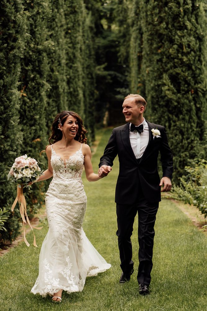 A romantic wedding couple embraces in sunlit garden setting at golden hour.