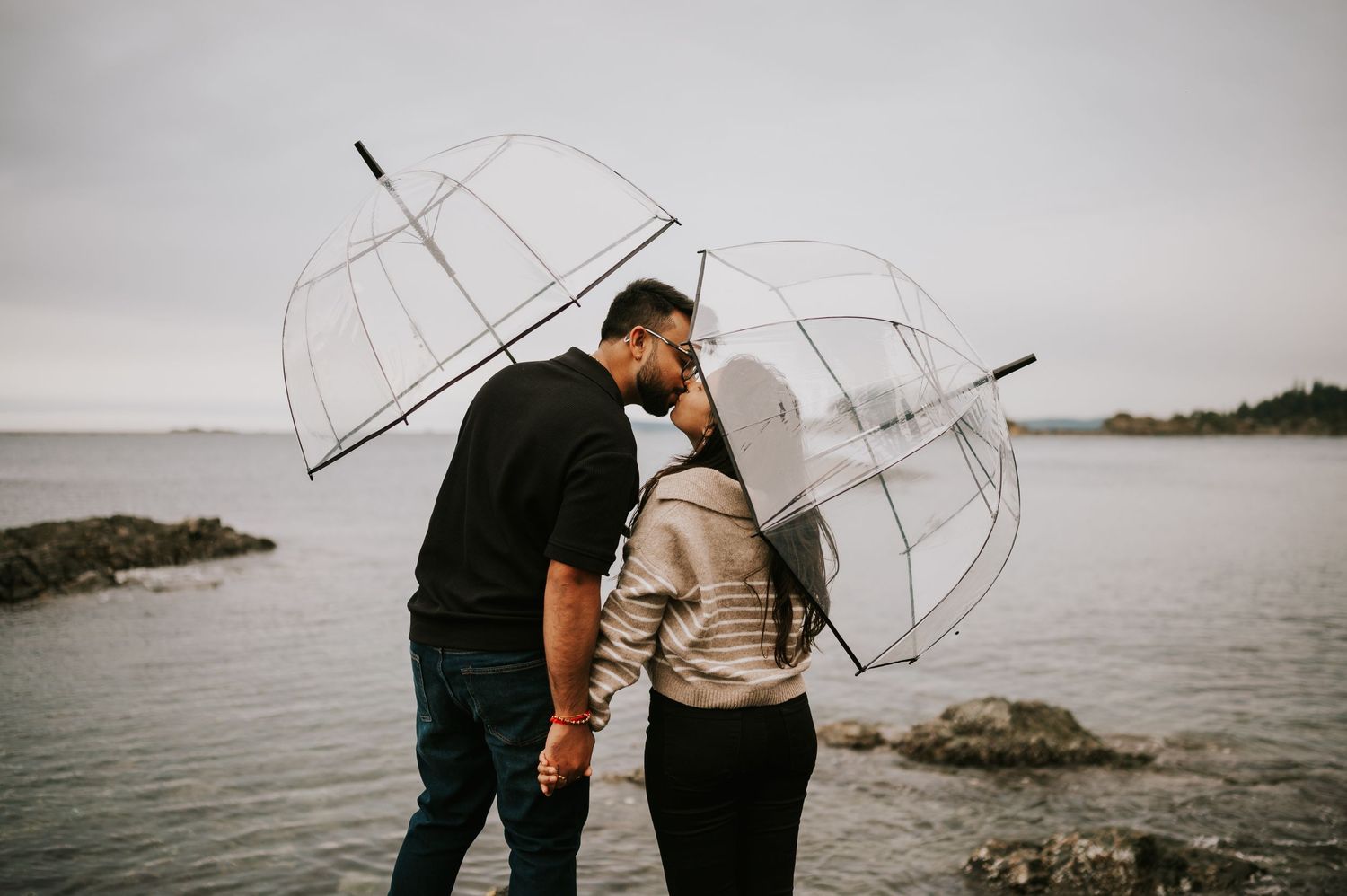 Rainy Neck Point Park, Nanaimo, Vancouver Island Engagement Photoshoot of couple under two umbrellas kissing for photographer soulfull photo