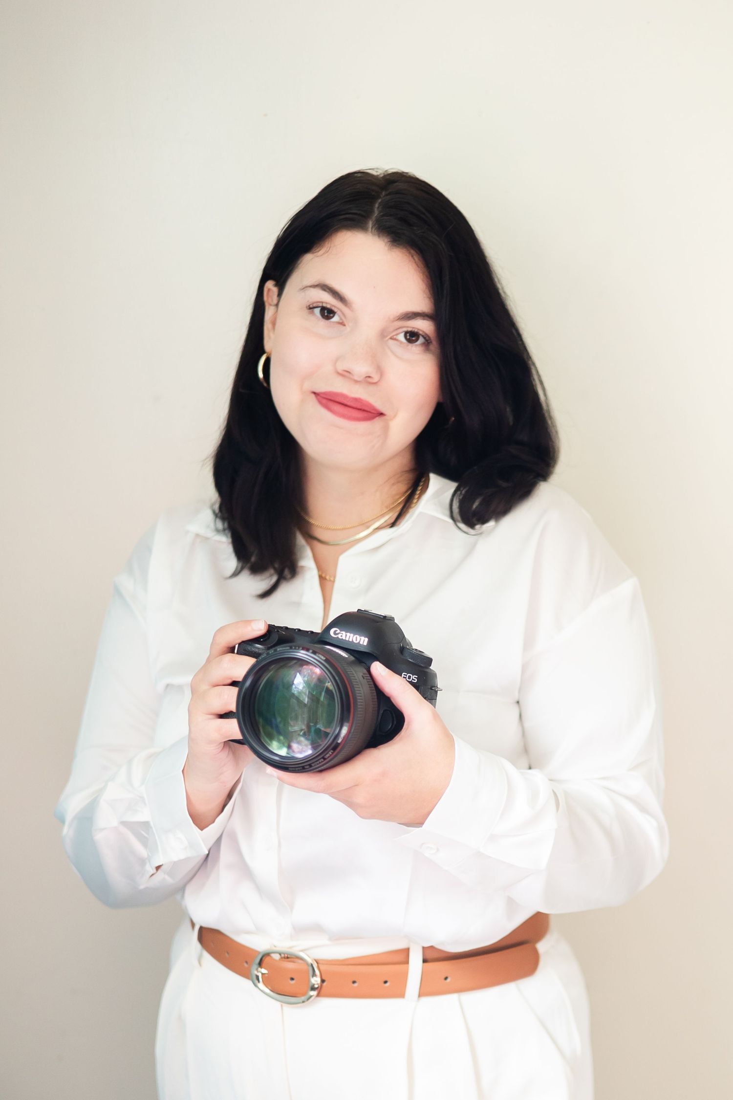 A person in a white button-down shirt poses with a camera in a series of four professional headshots.