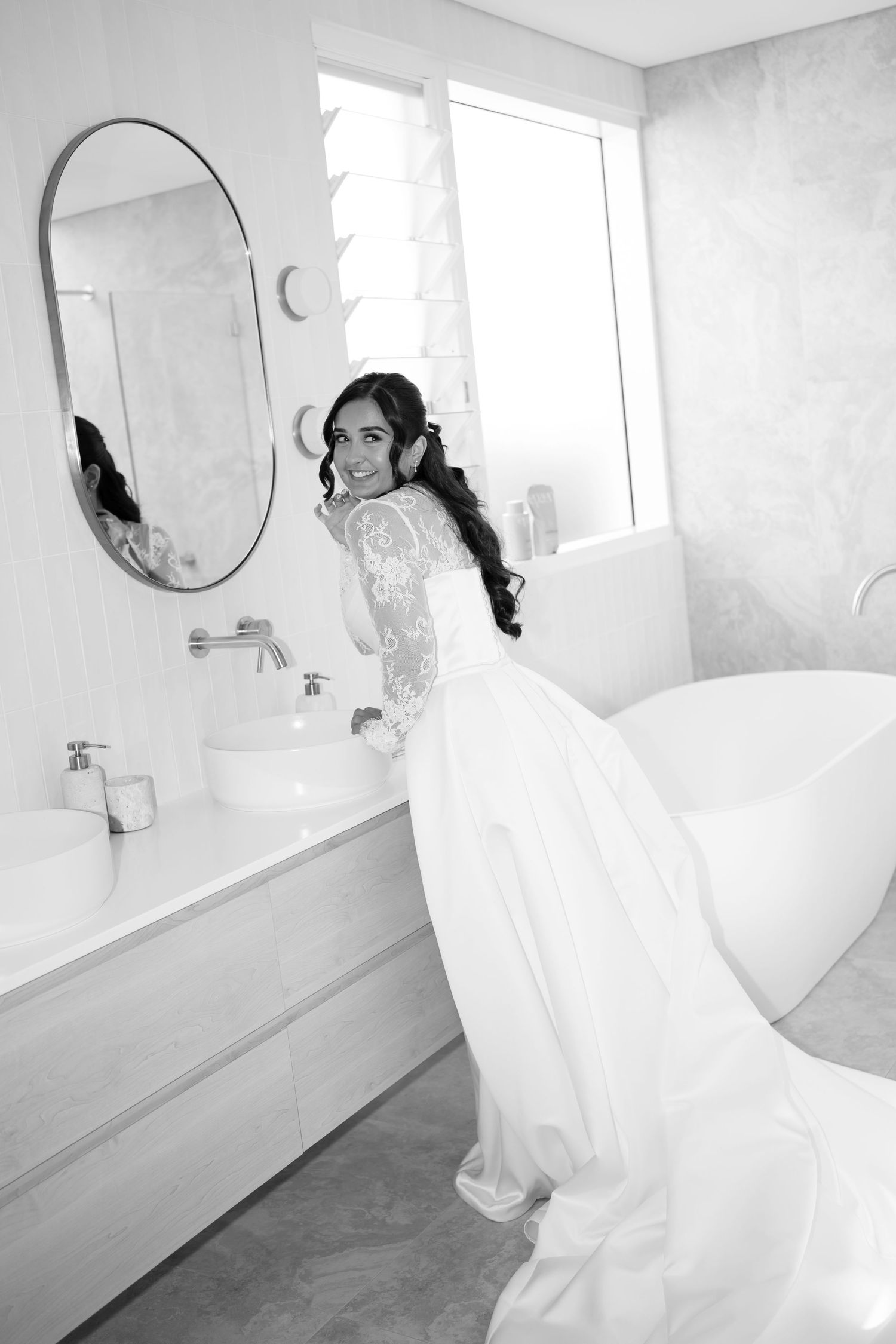 A series of minimalist white bathroom interior photos showing curved walls, mirrors, and modern fixtures.