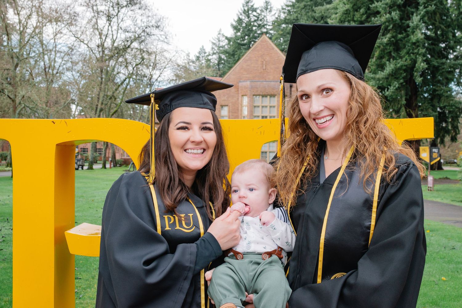 Nursing graduate at Pacific Lutheran University holding her baby during graduation photos in Tacoma, Washington.