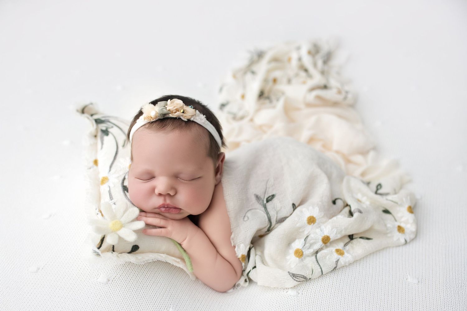 Sleeping newborn in light gray outfit against navy backdrop.