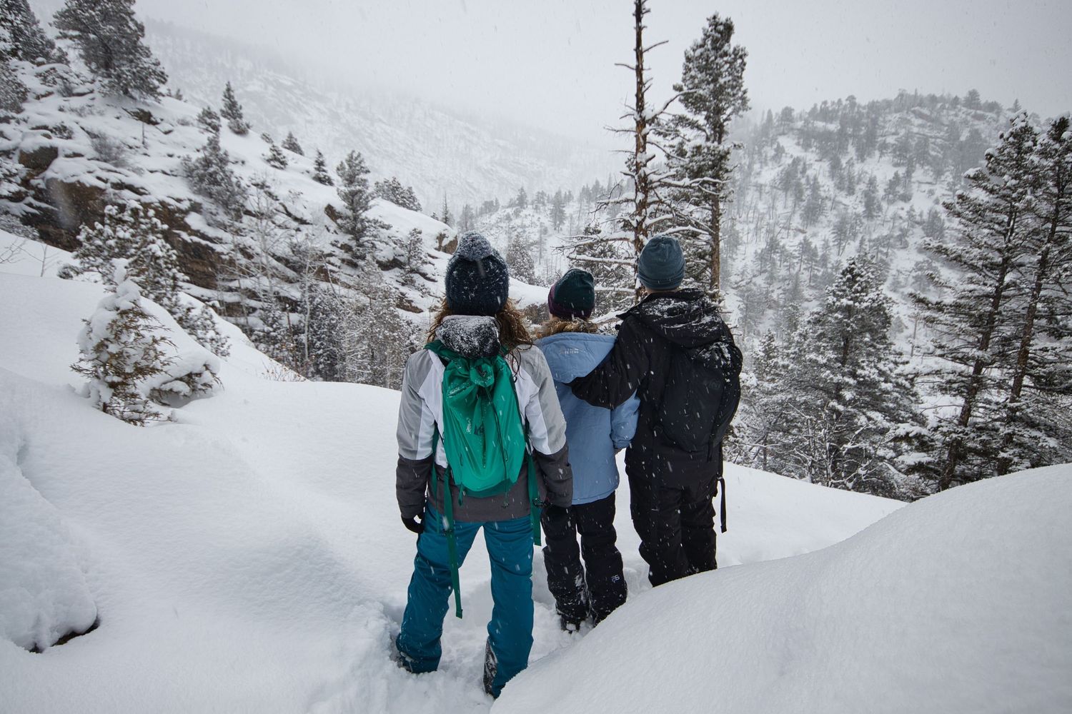 1 foot of snow on the trail and a family taking in the view through the storm on Cub Lake trail in Rocky Mountain National Park. Pixcapades