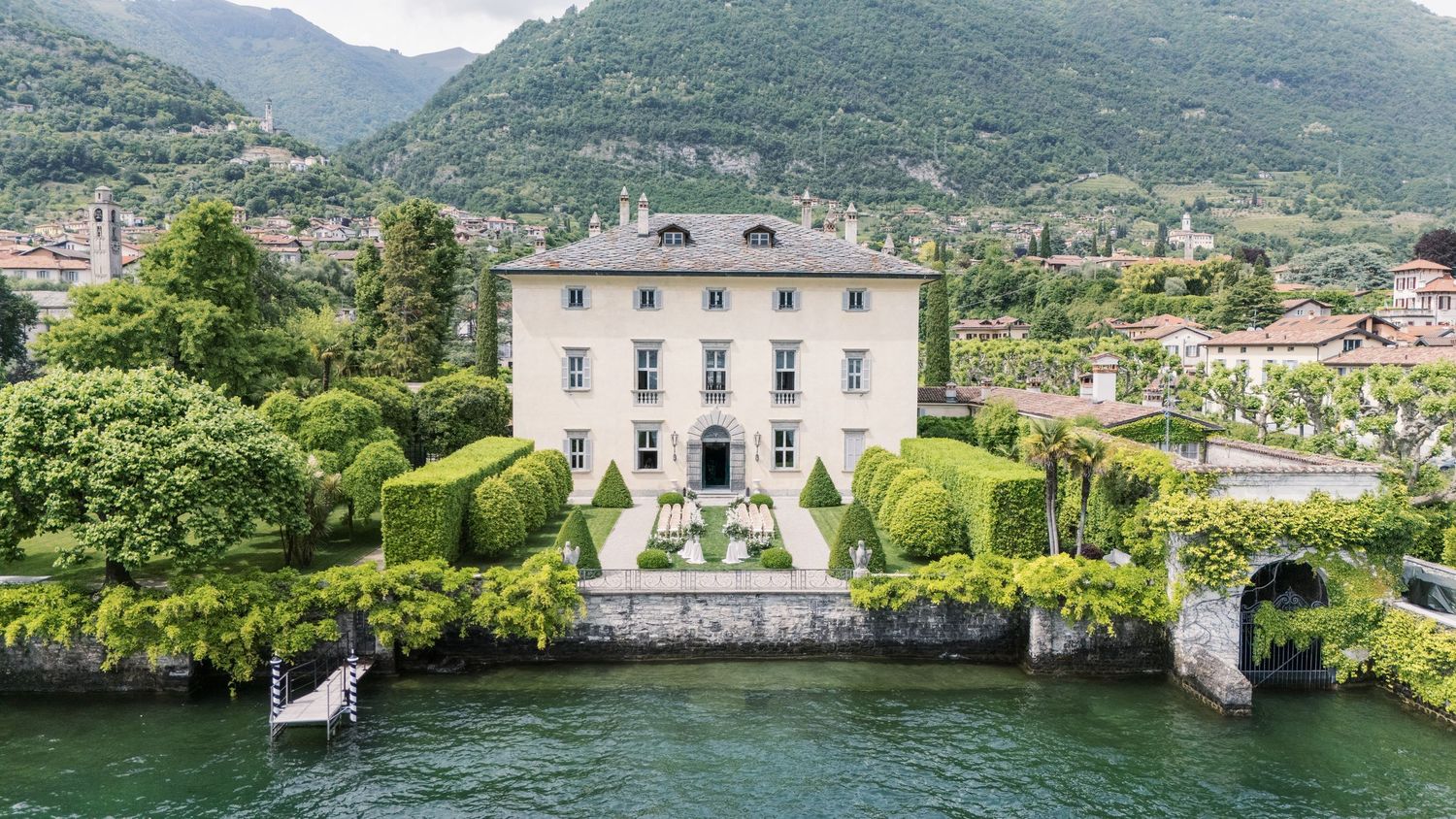 Panoramic view of Italian lakeside villas and mountains surrounded by lush greenery.