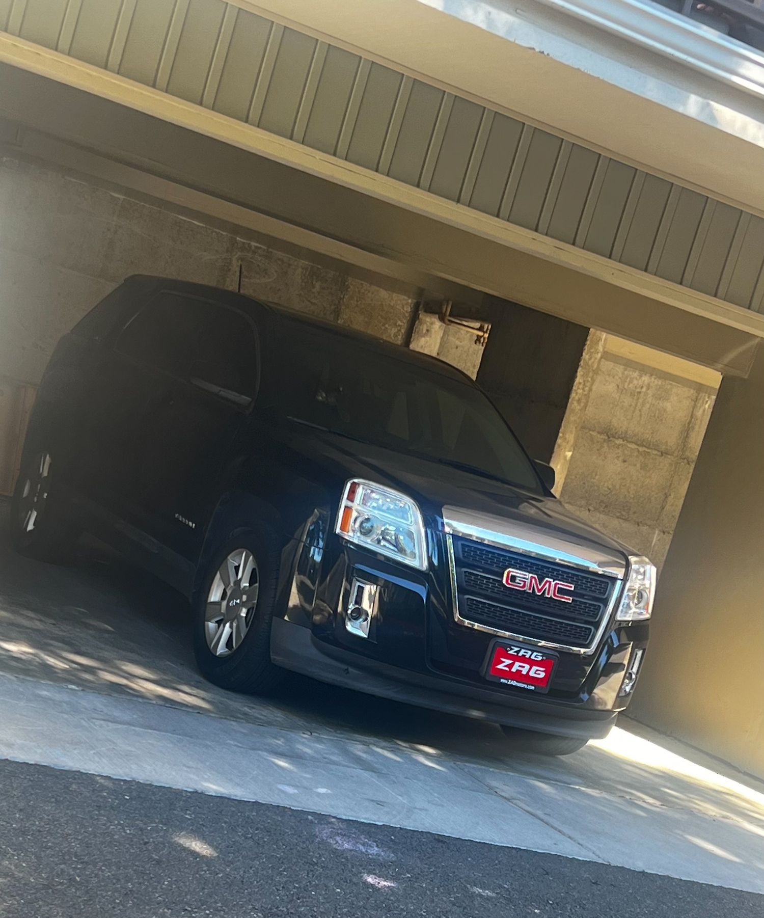 Black GMC SUV parked inside a covered parking garage entrance with angled lighting.