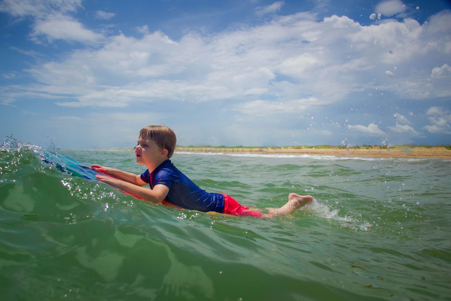 Boy on boogie board at Matagorda beach during family photography session.