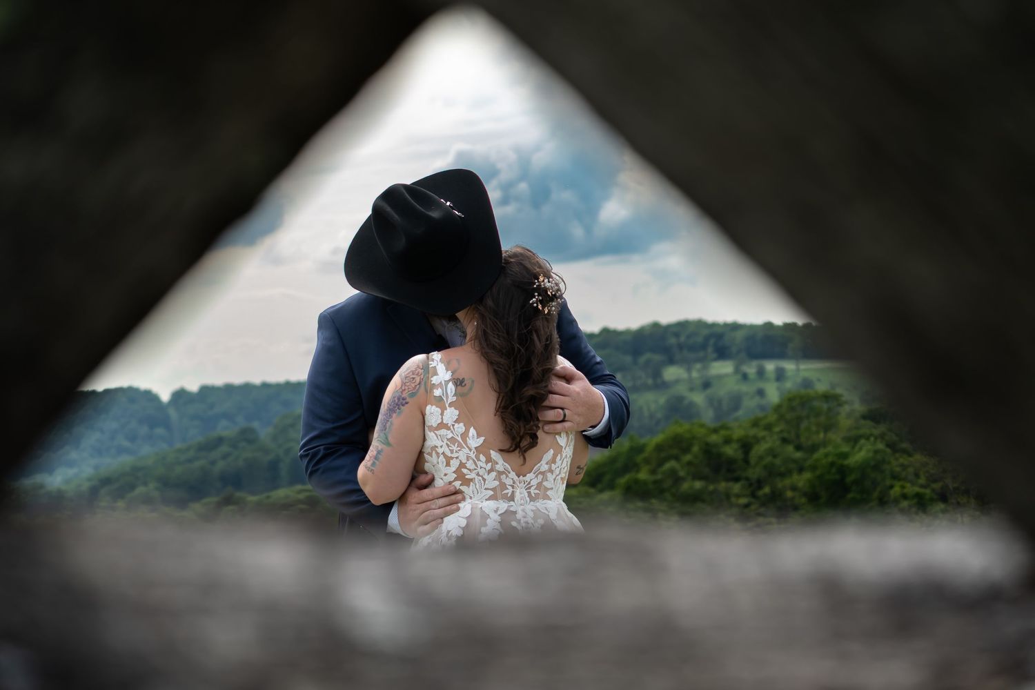 A romantic couple in wedding attire share an intimate moment in a lush outdoor mountain setting. West Virginia wedding