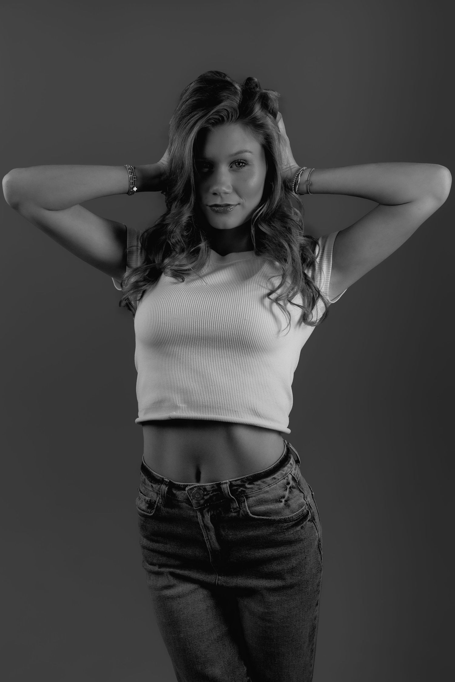 Black and white fashion photo series showing model in casual attire posing with hands behind head in artistic sequence.