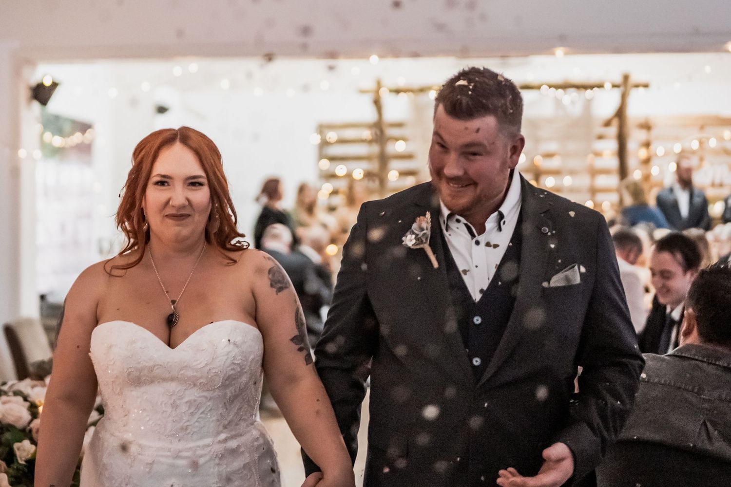 Wedding guests enjoying themselves on the dance floor at an indoor reception celebration with white decor.