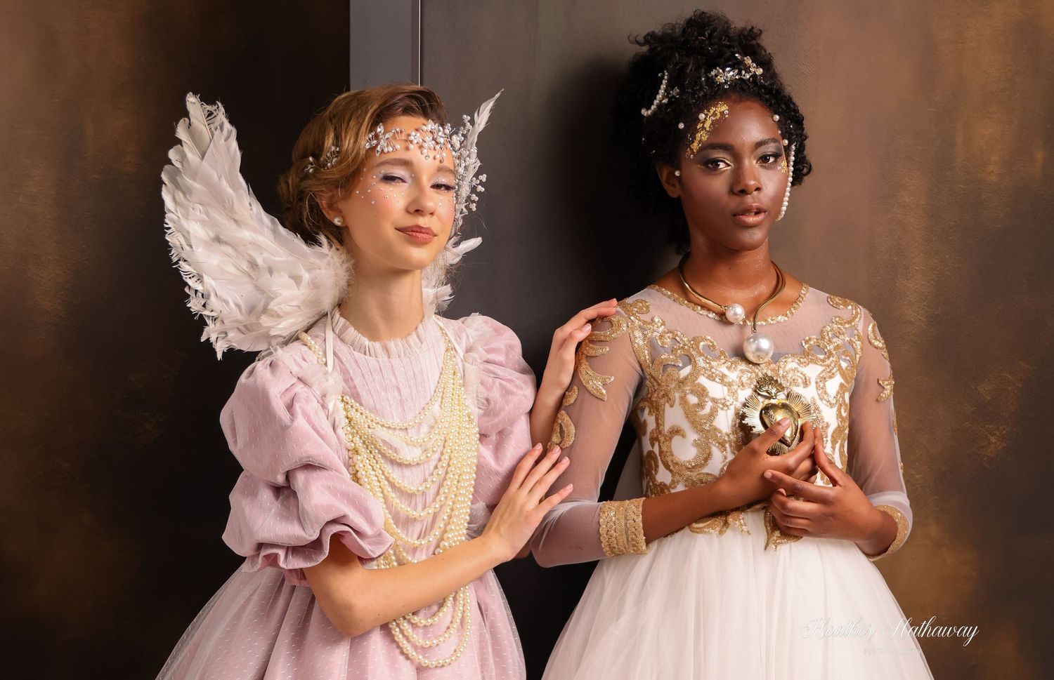 Two young girls in pink and white dresses pose together while holding teacups during a photoshoot.