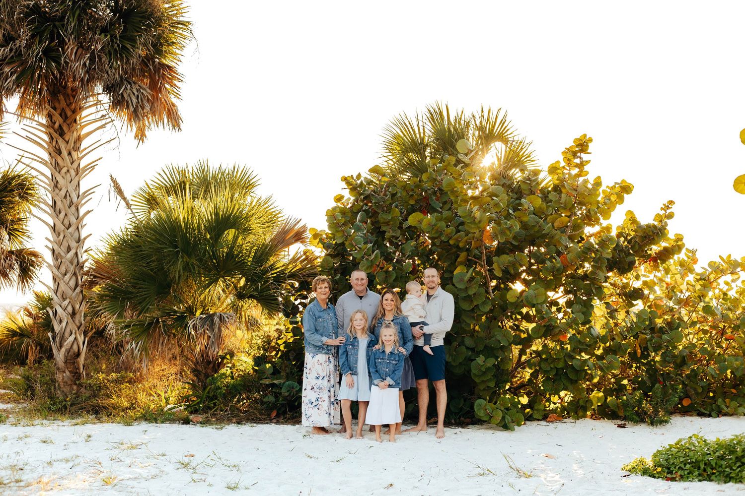 Family members sit together on a wooden bridge during a sunset photo session in a park.