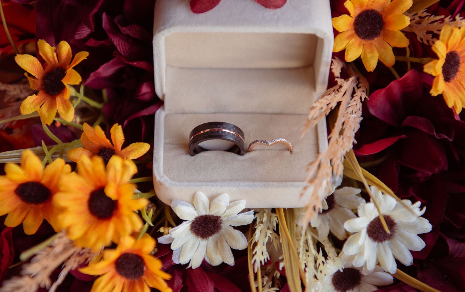 A colorful floral arrangement with sunflowers, daisies, and burgundy blooms against a white backdrop.