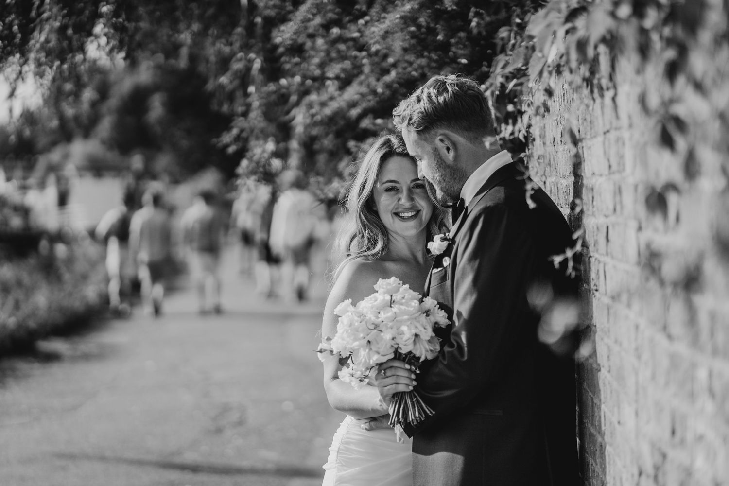 A black and white wedding photo series showing intimate moments between a couple in an outdoor garden setting.