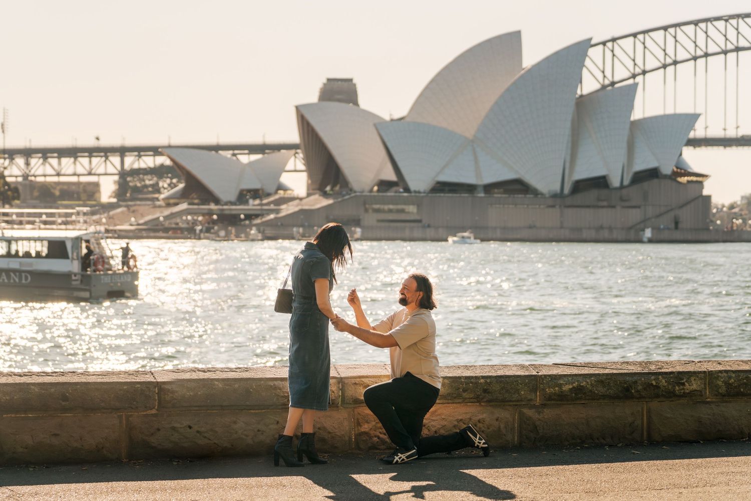 Man proposes women in front of the harbour wall overlooking Sydney Opera House and Harbour Bridge during sunset photoshoot