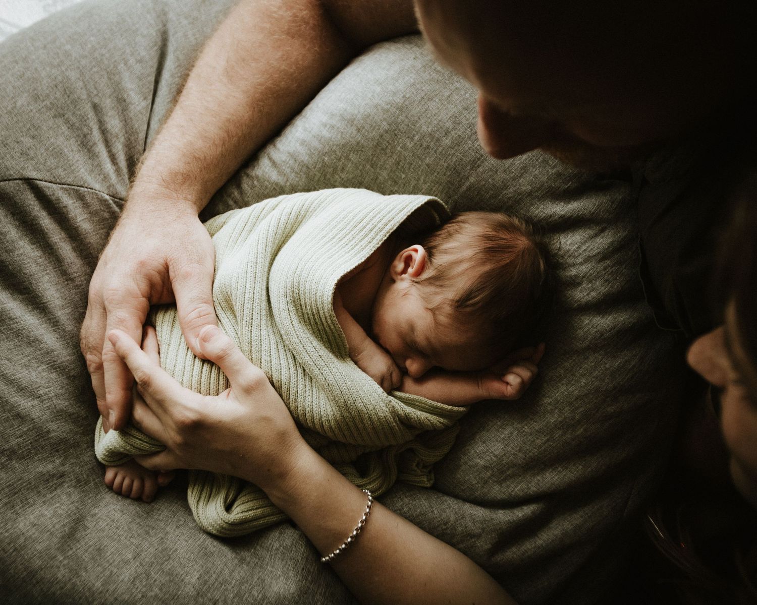 A tender moment captured of a swaddled newborn being held in loving arms.