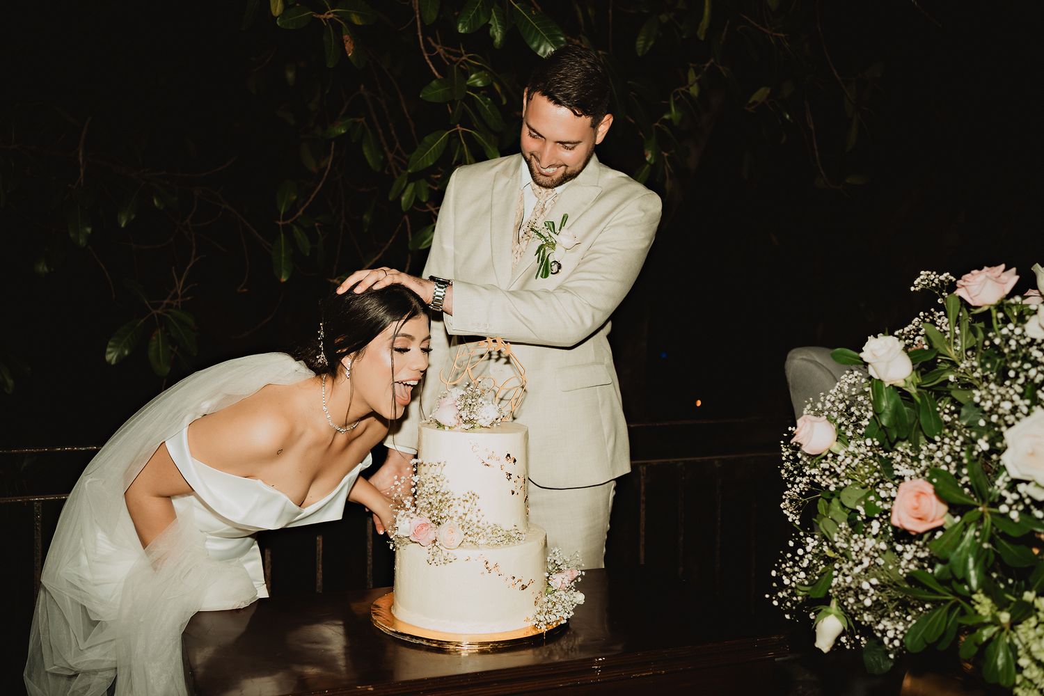 Vintage flash photo of the couple playfully cutting into their wedding cake, a fun and lively moment captured