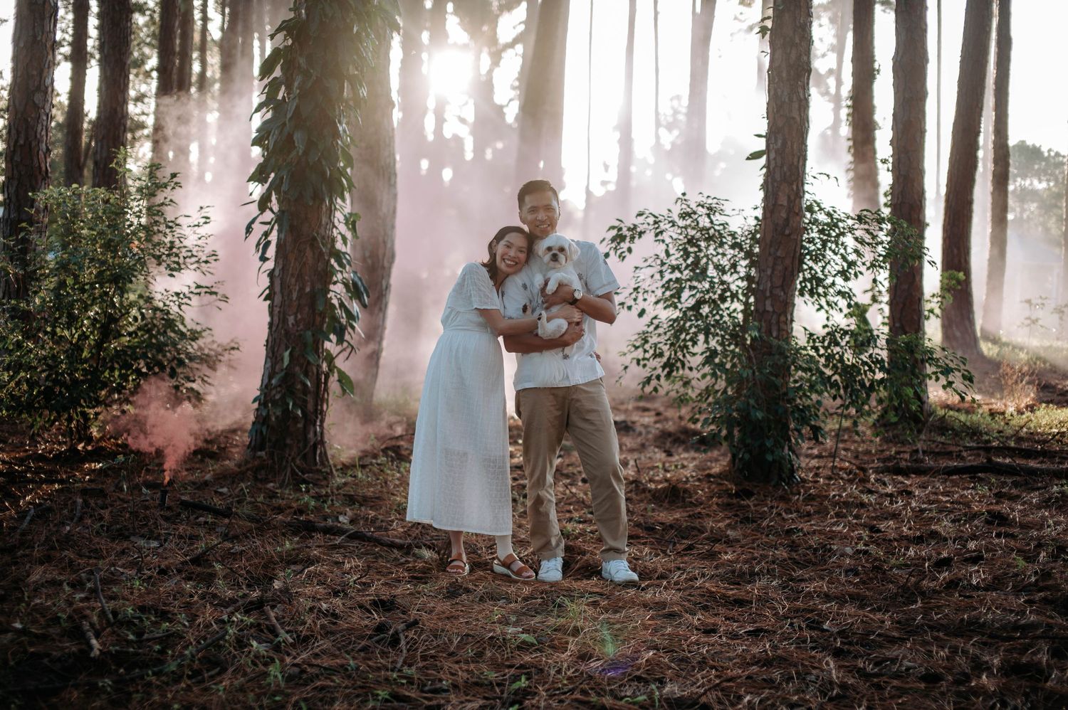 Couple sharing a romantic moment in a forest with pink smoke effects.