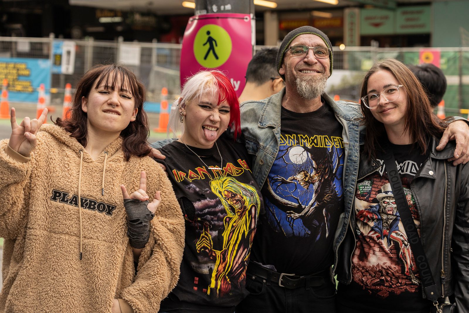 A middle-aged man and his three daughters posing in the street wearing Iron Maiden t-shirts