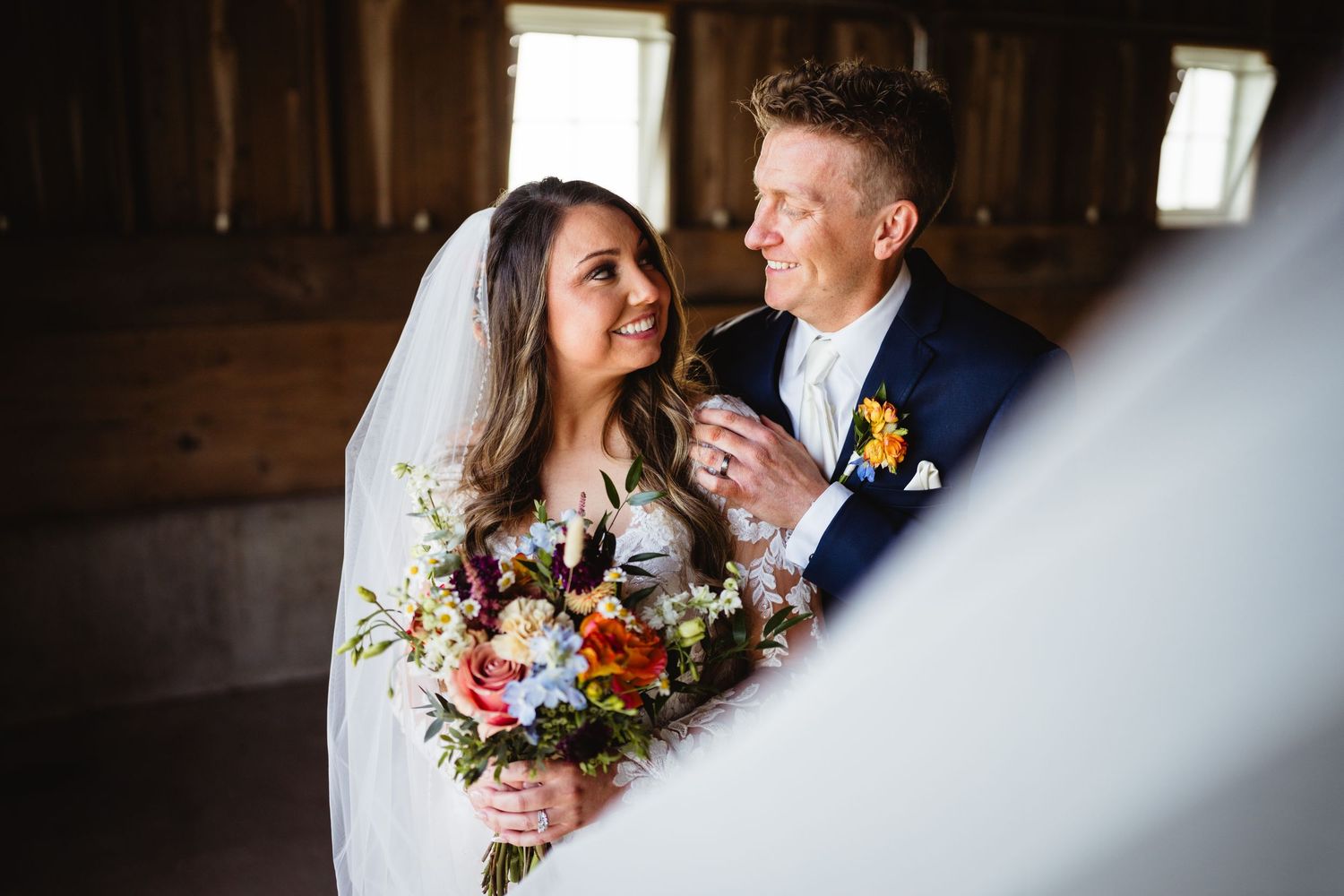 Wedding party lifts colorful bouquets in celebratory moment during outdoor sunset ceremony.
