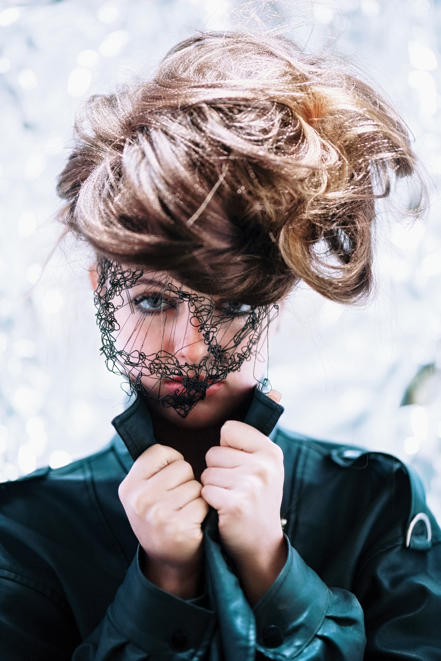 Artistic portrait featuring lace veil details and upswept hair against snowy background.