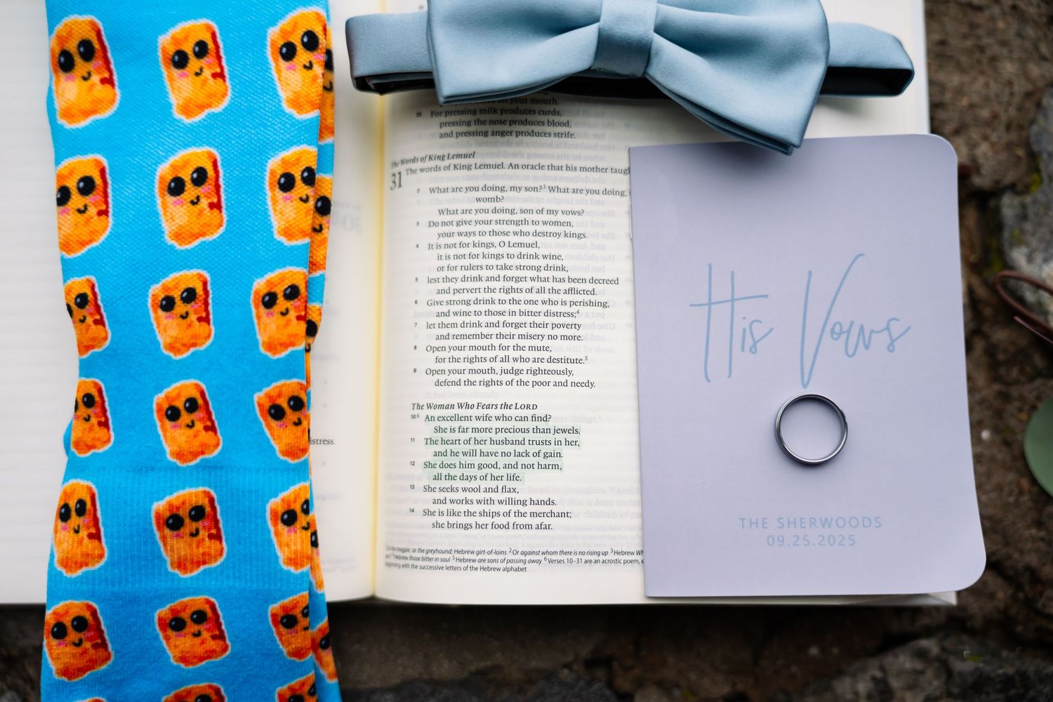 A light blue bowtie rests on an open book with orange skull pattern paper visible in the background.