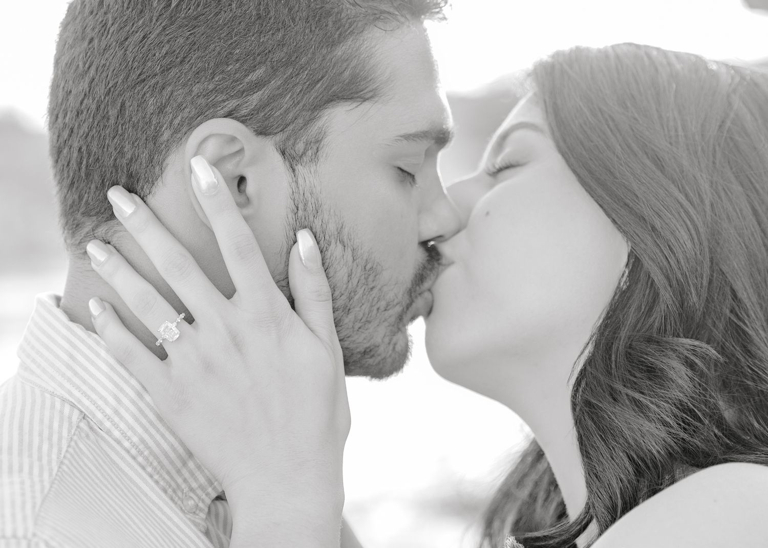 A romantic black and white photo captures a tender moment between a couple sharing a kiss.