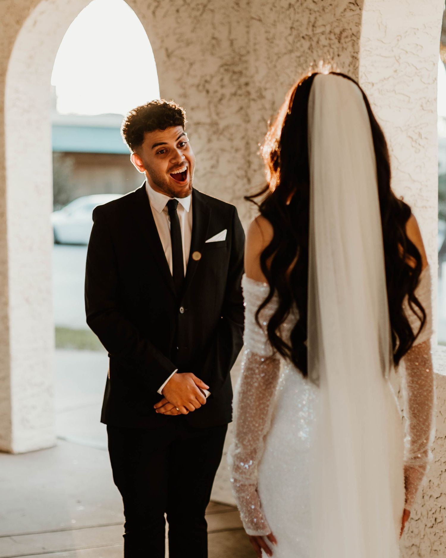 Wedding couple sharing joyful moment in arched hallway.