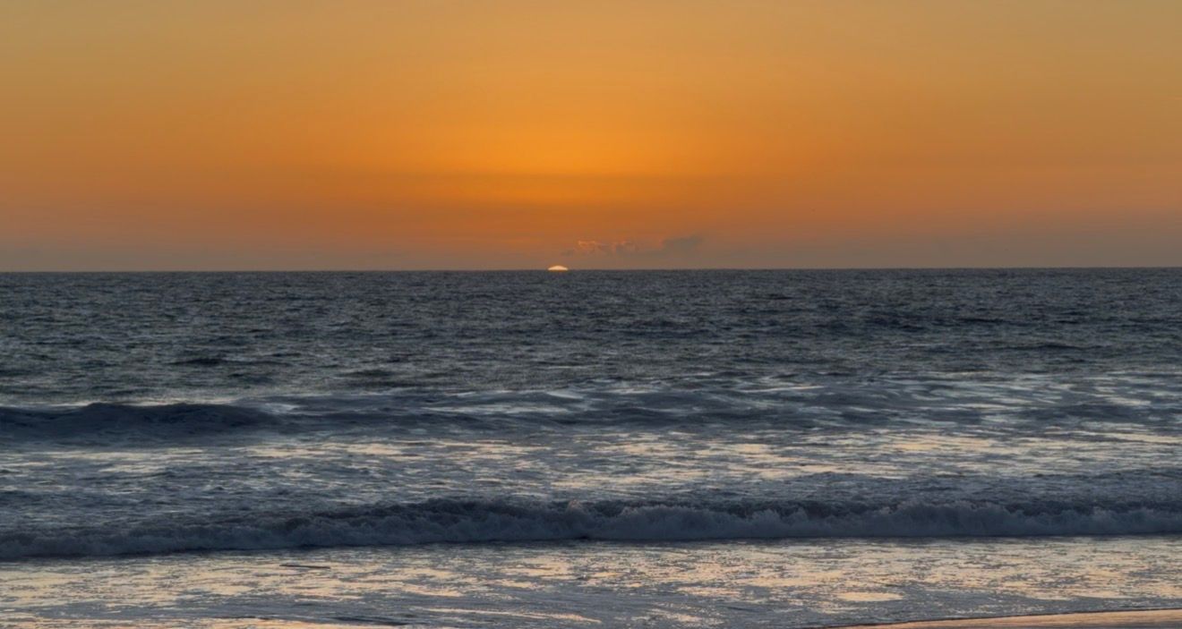 A series of ocean sunset photos showing the sun descending over calm waters with waves rolling onto the shore.