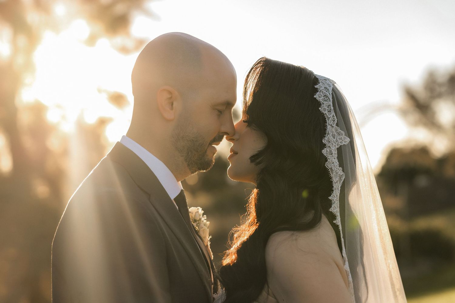 Bride and groom kissing at blue-draped wedding arch, bride holding blue and white floral bouquet.