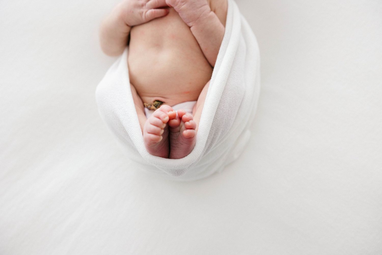 A series of four close-up photos showing a baby's tiny hands and feet against a white background.