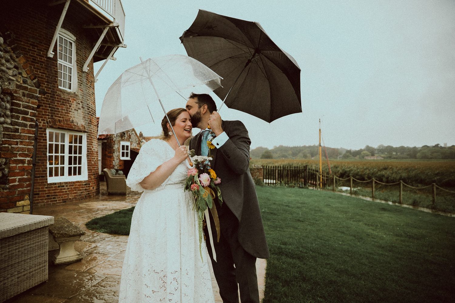 Bride and groom share a romantic moment under a floral arch with wisteria blooms at an elegant wedding venue.