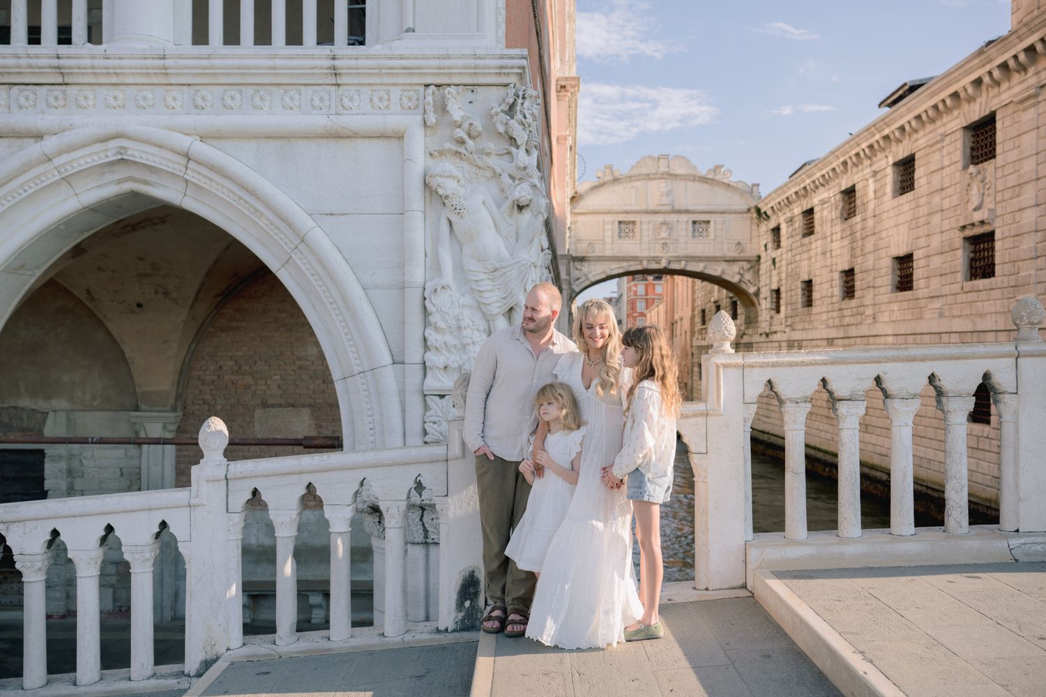 Family of four posing near the Bridge of Sighs in Venice, Italy, with historic architecture.