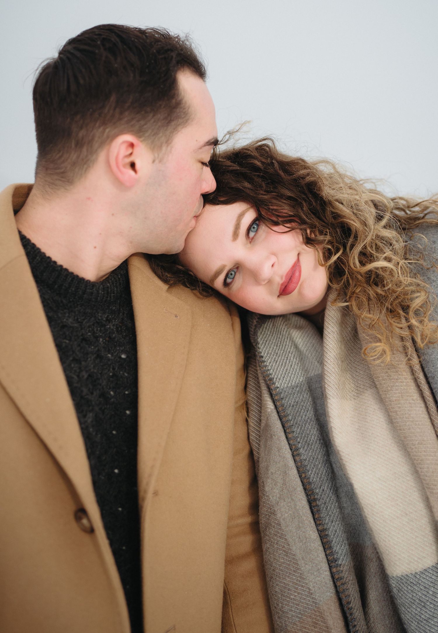 Romantic couple in warm winter coats sharing intimate moments in a series of candid photos.